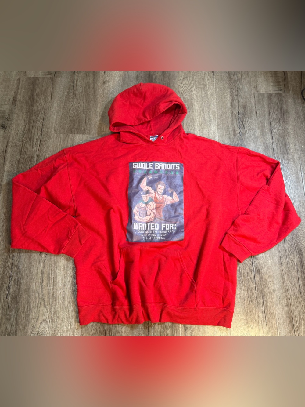 a red sweatshirt featuring a *Home Alone*-style print titled "Swole Bandits"